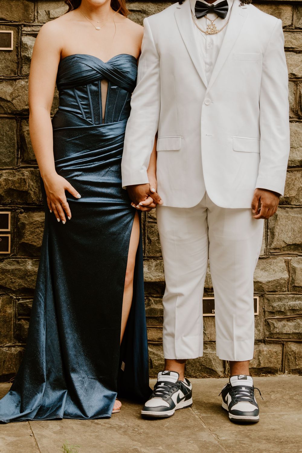 Wedding party members shown from waist down wearing formal attire and casual sneakers.