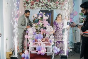 Indoor party celebration with sparklers, purple balloons, and floral decorations creating a festive atmosphere.