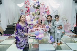 A group of people celebrating at a baby shower with pink decorations and gifts in a bright indoor setting.