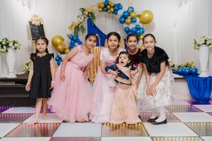 A festive birthday party scene with blue and gold balloon decorations and people gathered for a celebration.