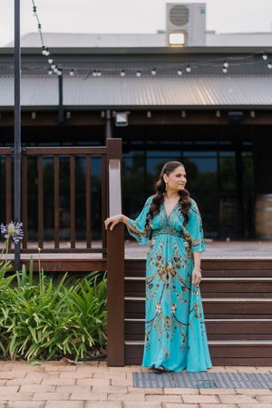 A series of photos showing a person in a turquoise floral dress posing on wooden benches at an outdoor venue.