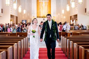 A couple walks down a church aisle together smiling after their wedding ceremony on Oahu.