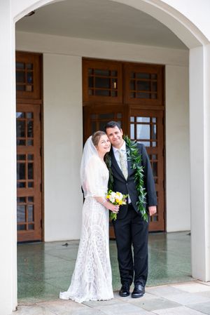 A couple shares a tender moment under an arched walkway during their wedding photoshoot on Oahu.