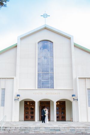 Bride and groom under the white church exterior with arched windows and wooden double doors viewed from three different angles on Oahu.
