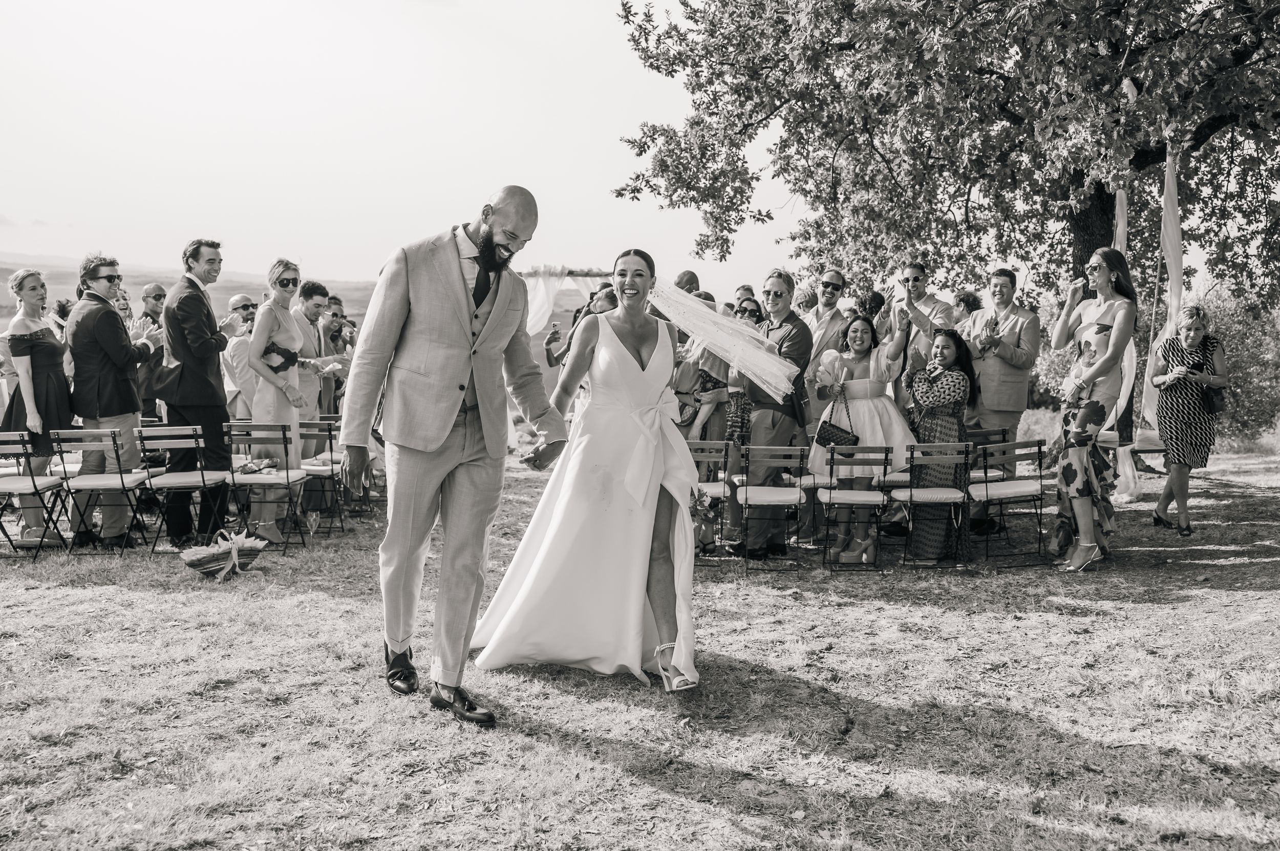 A series of black and white wedding photos showing couples walking through an outdoor garden ceremony setting.