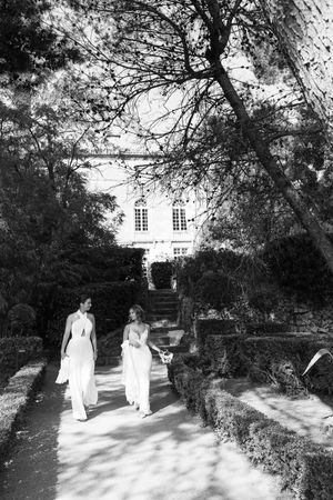 A sequence of black and white photographs showing two people walking along a garden path leading to a white house.