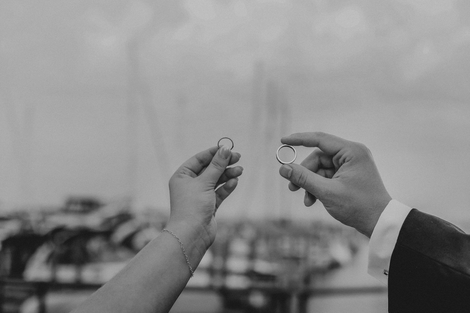 Two rings being held up at a marina after a wedding