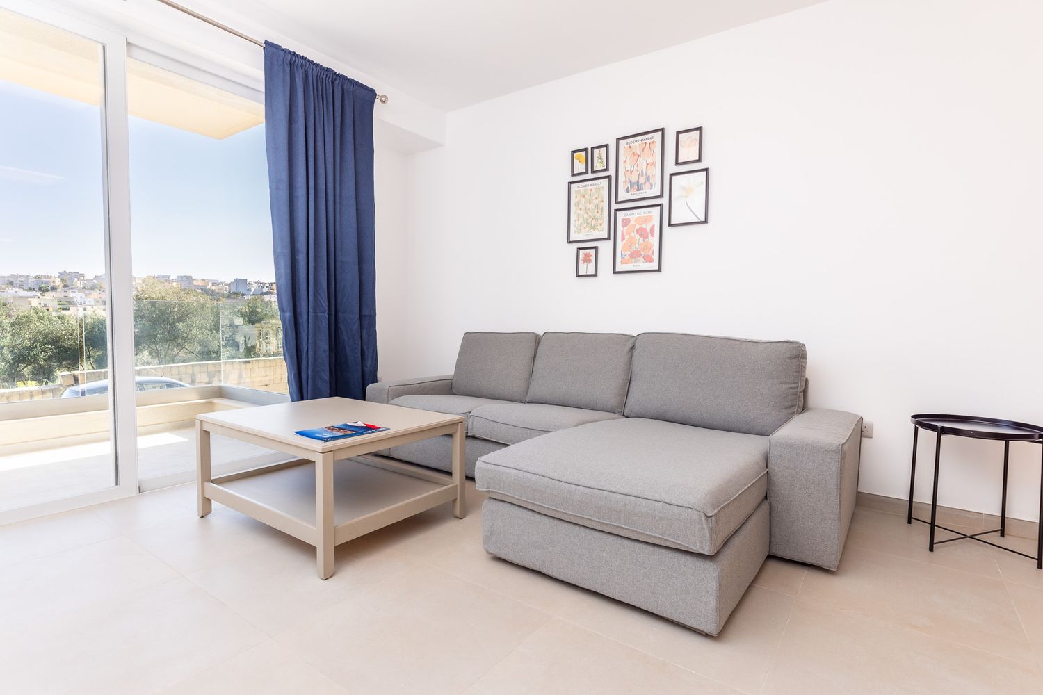 Bright living room with gray sectional sofa, wooden coffee table, and large balcony sliding doors.