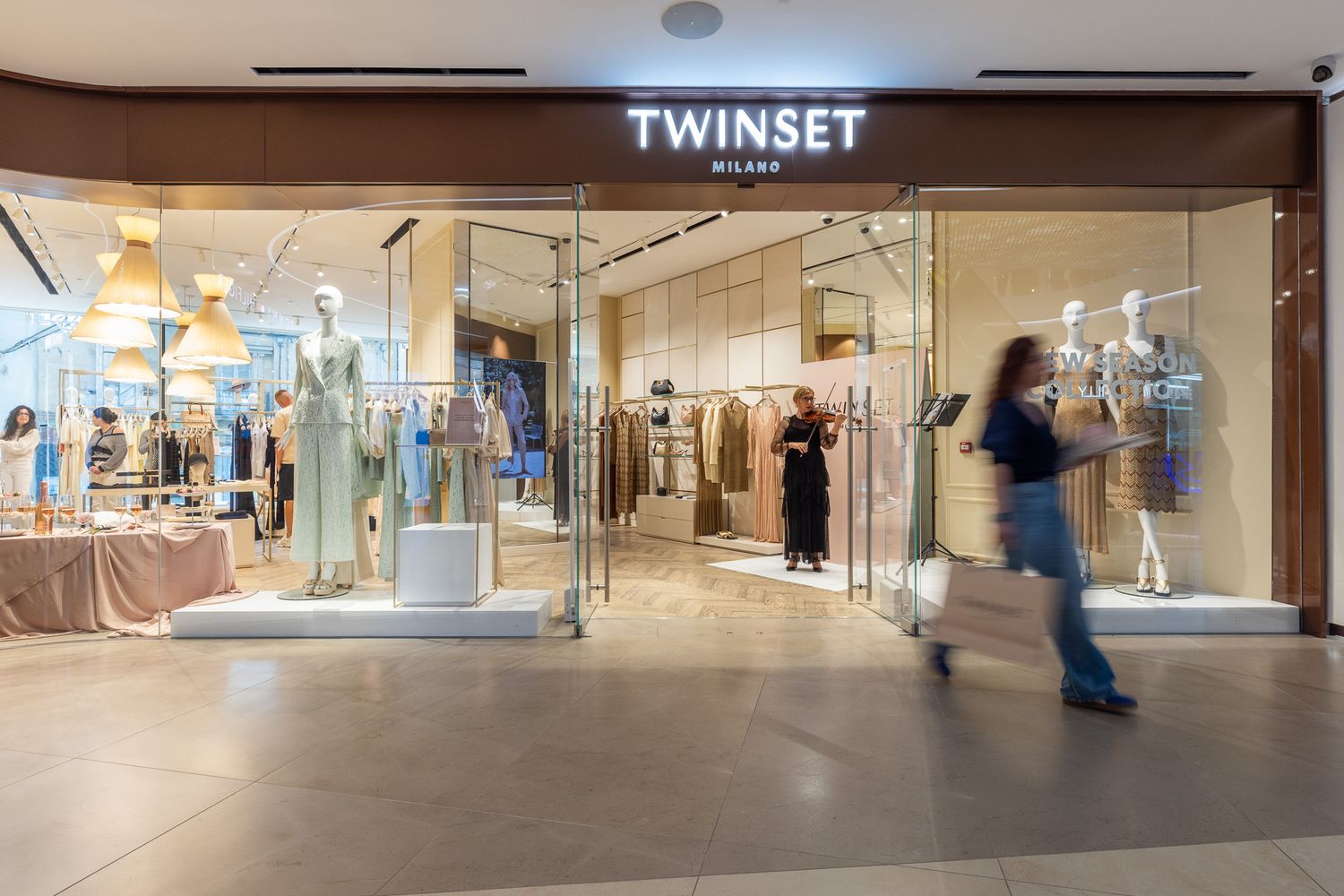 Twinset Milano retail store entrance in a shopping mall with mannequins and shoppers inside.