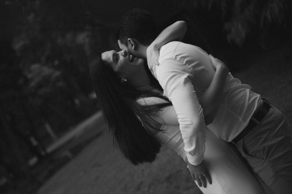 Black and white romantic couple embracing outdoors, woman leaning back with long hair flowing, man holding her close.