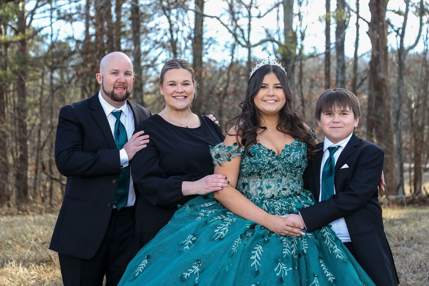 Family portrait before quinceañera celebration with parents and daughter in formal attire, outdoor setting with soft strobe lighting