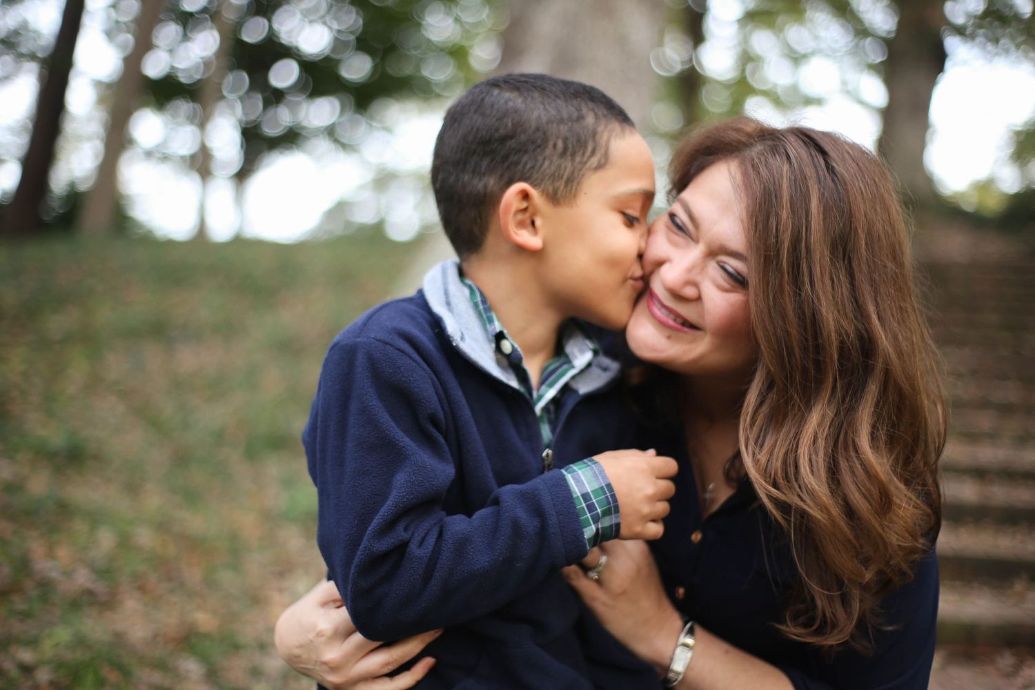 Mother and son snuggle and son gives mom kiss on check during fall photos.