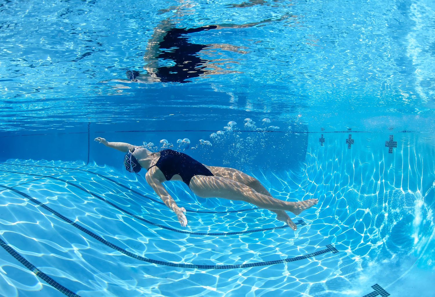 Harrison High School female swimmer underwater getting ready to swim backstroke in the deep end of the pool.