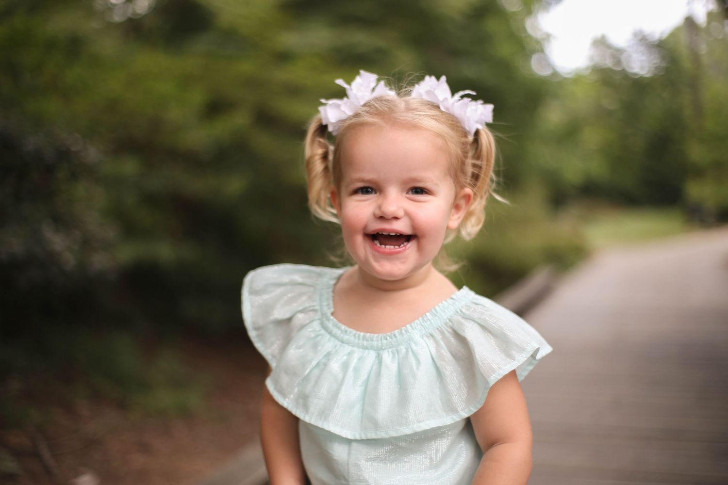 Happy girl toddler in pigtails playing with the photographer in the garden in Glencarin Gardens in Rock Hill, SC.