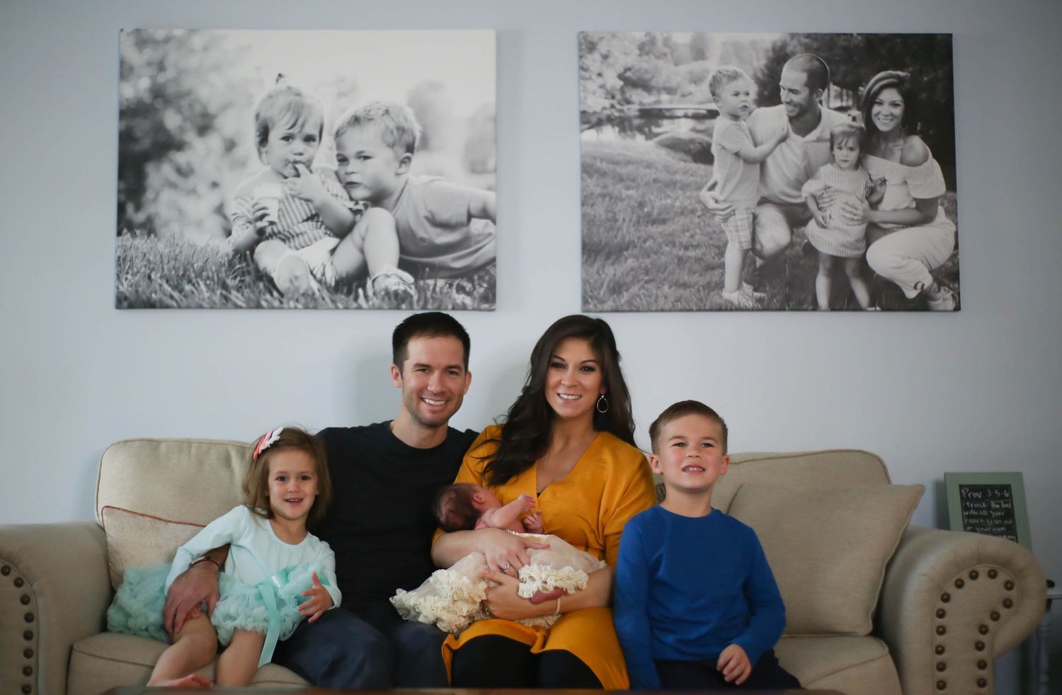 Family of 5 pose in front of black and white photos on the wall that were taken by the same photographer.