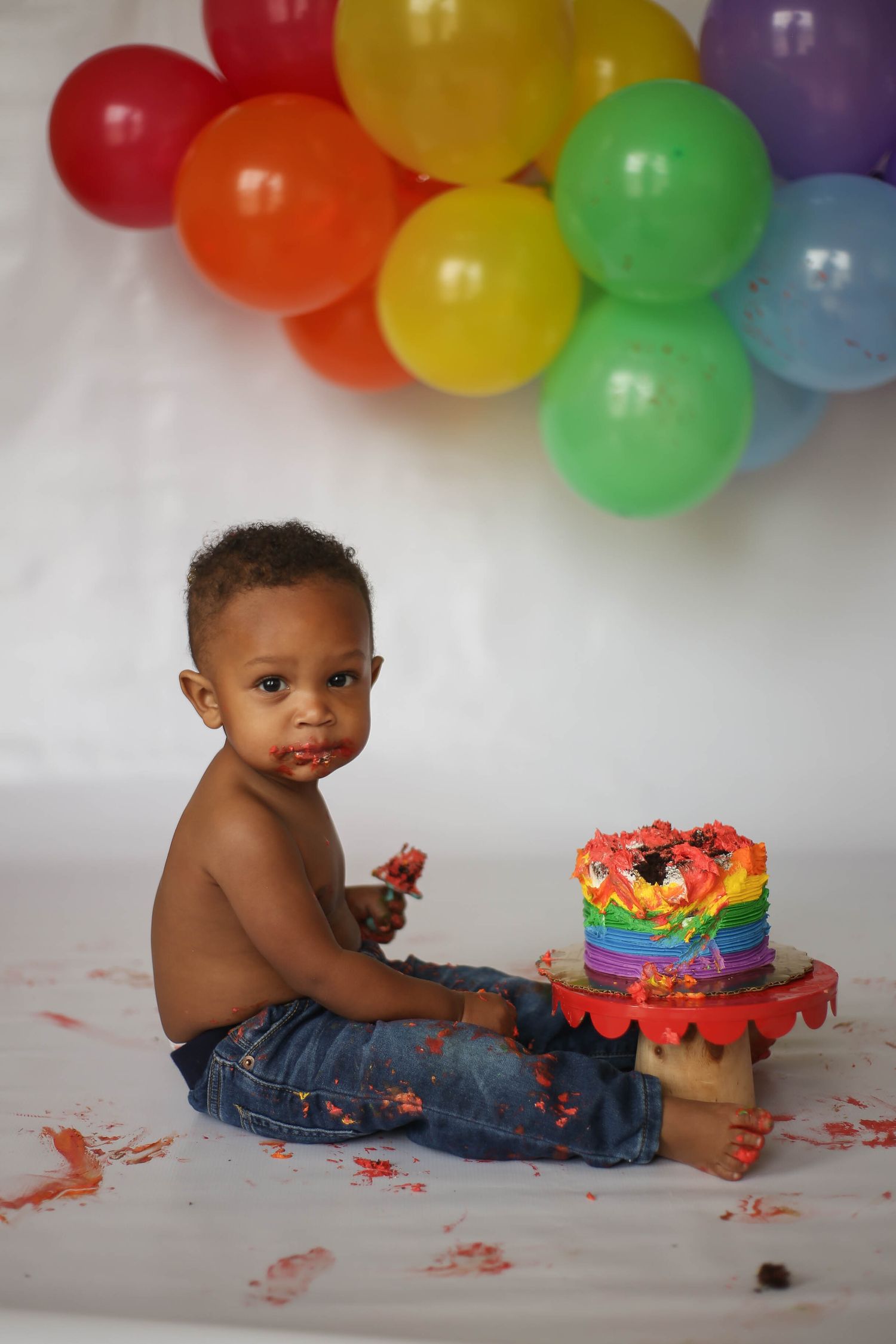 One year old smash cake session.  Little boy with rainbow cake and balloons.
