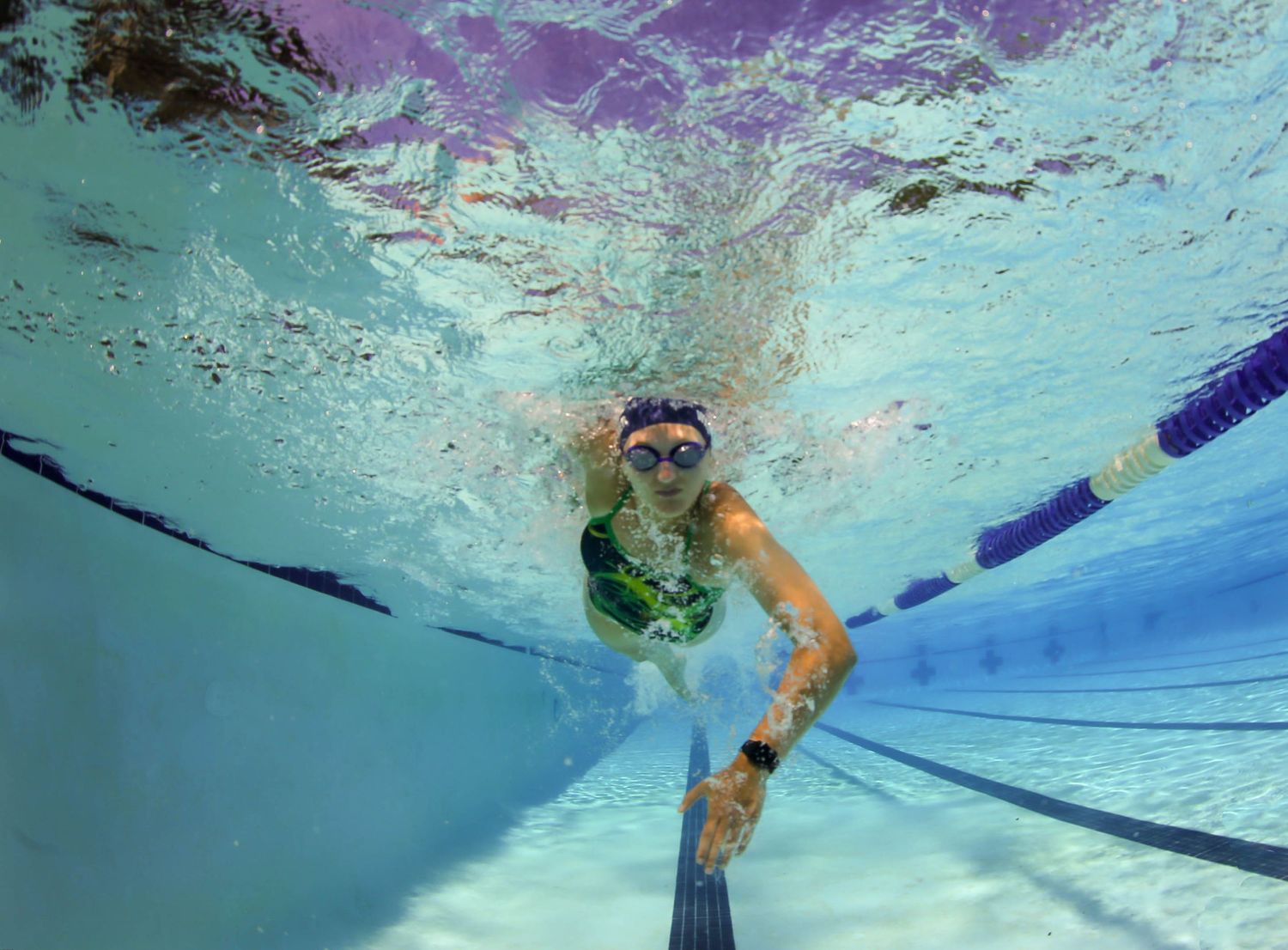 Female high school swimmer swimming freestyle underwater captured swimming towards the camera.