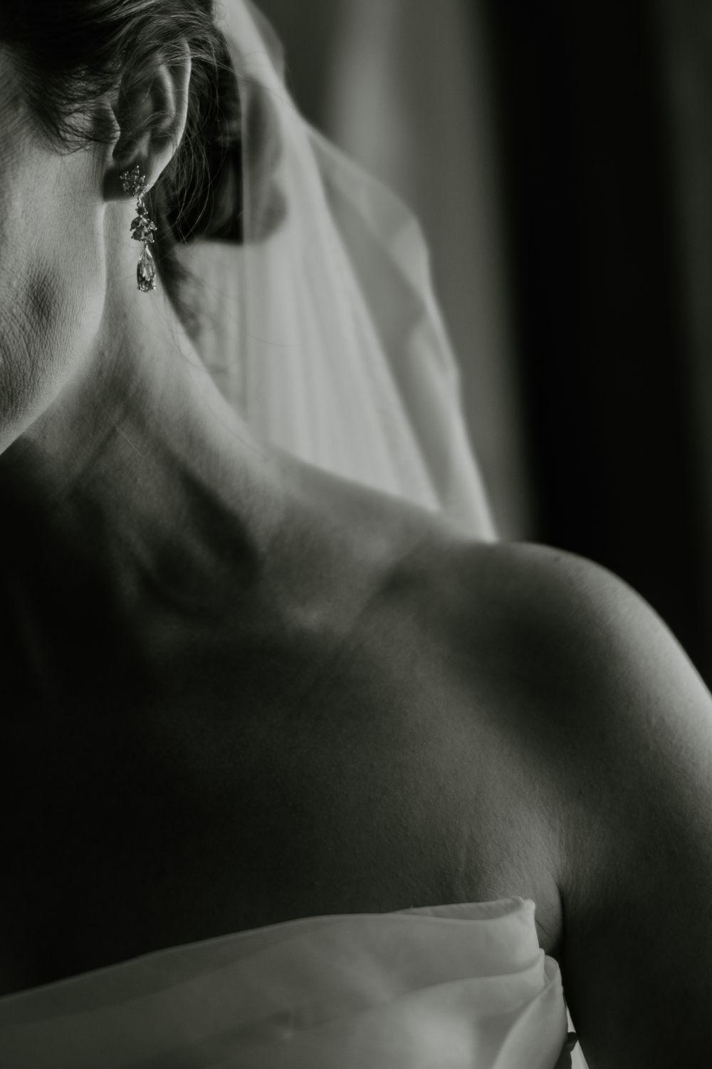 Black and white artistic photograph showing a person's bare shoulder and neck in dramatic lighting and shadow.
