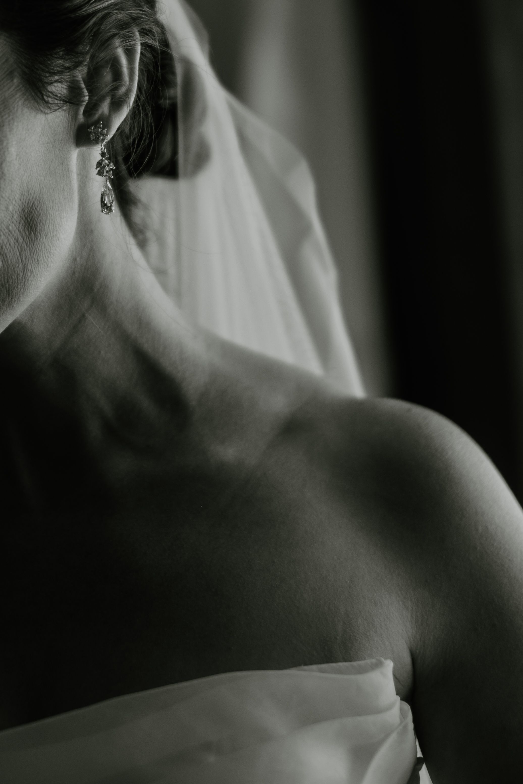 Black and white artistic photograph showing a person's bare shoulder and neck in dramatic lighting and shadow.