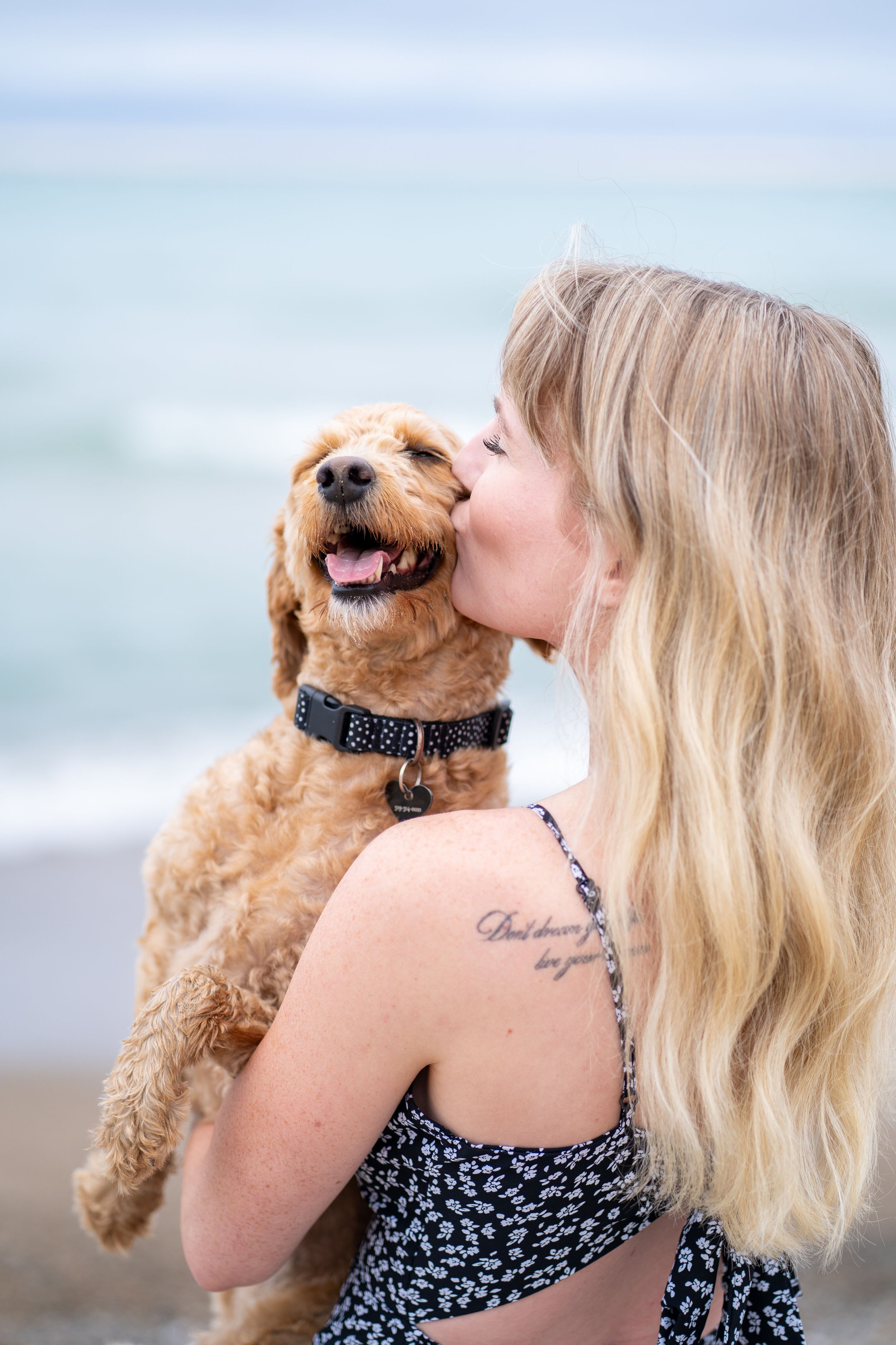 Golden dog receives affectionate kiss at the beach on a peaceful day.