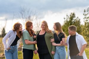 A candid group photo of family laughing together outdoors during golden hour.