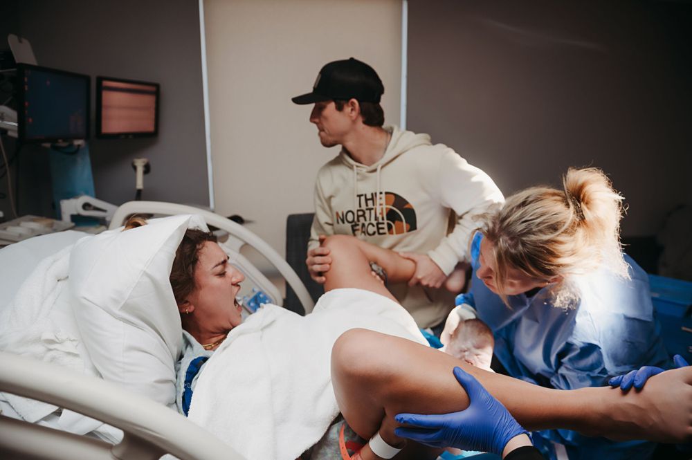Medical professionals work together with a patient in a hospital delivery room setting.