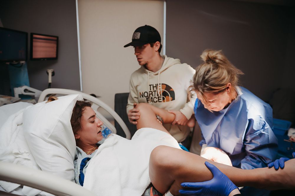 Healthcare workers assist a patient during labor in a hospital delivery room.