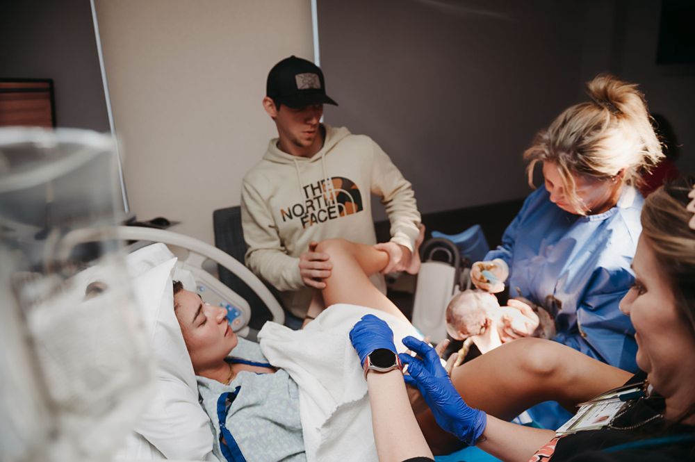 Medical care team attends to patient in bed while caregiver looks on during hospital visit.