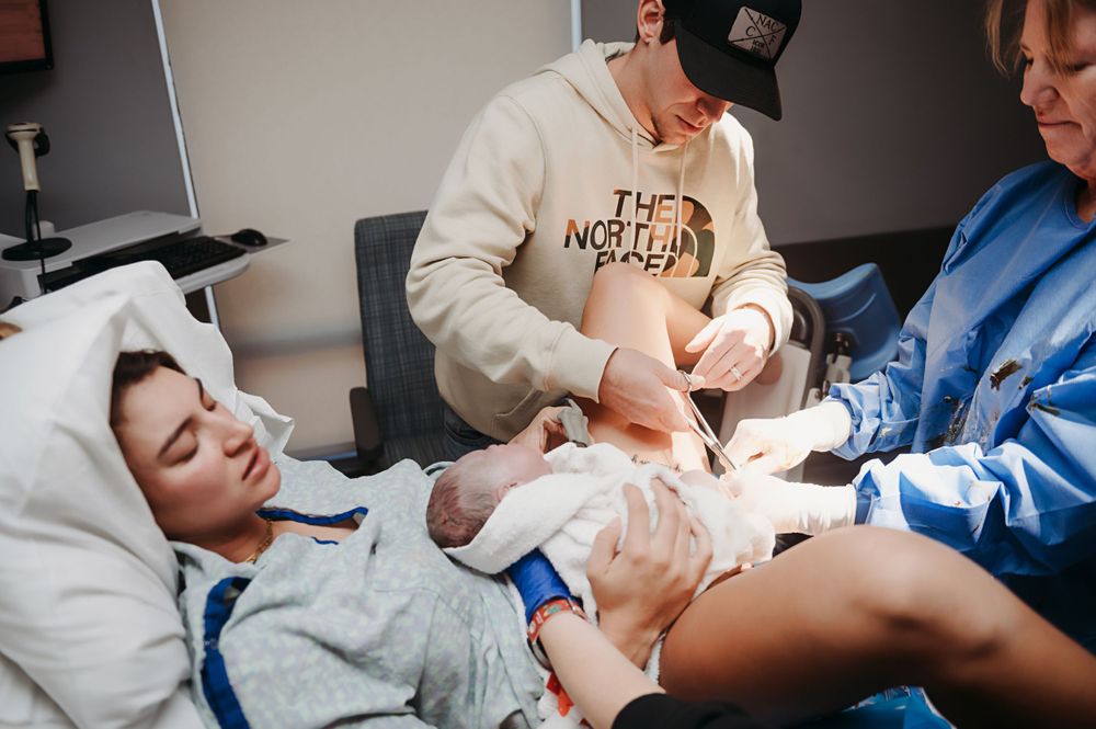 Dad cutting the umbilical cord of his new baby girl.