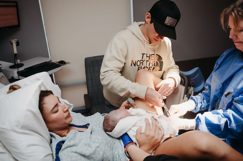 Dad cutting the umbilical cord of his new baby girl.