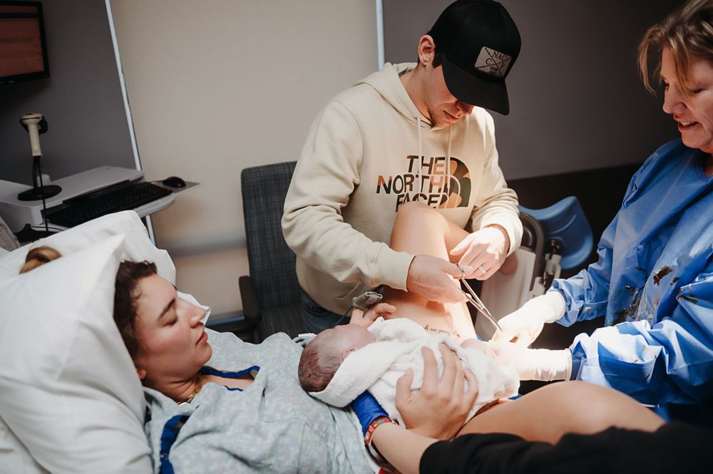 Dad cutting the umbilical cord of his new baby girl.
