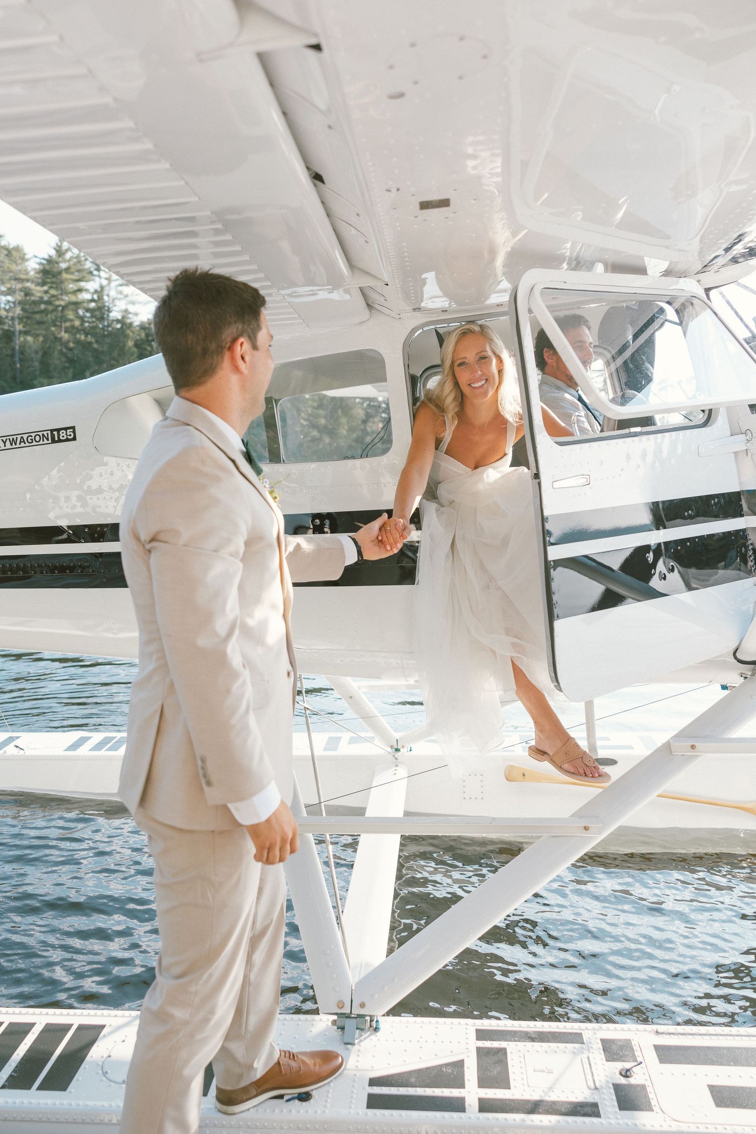A seaplane docked on calm waters with people in white attire boarding.