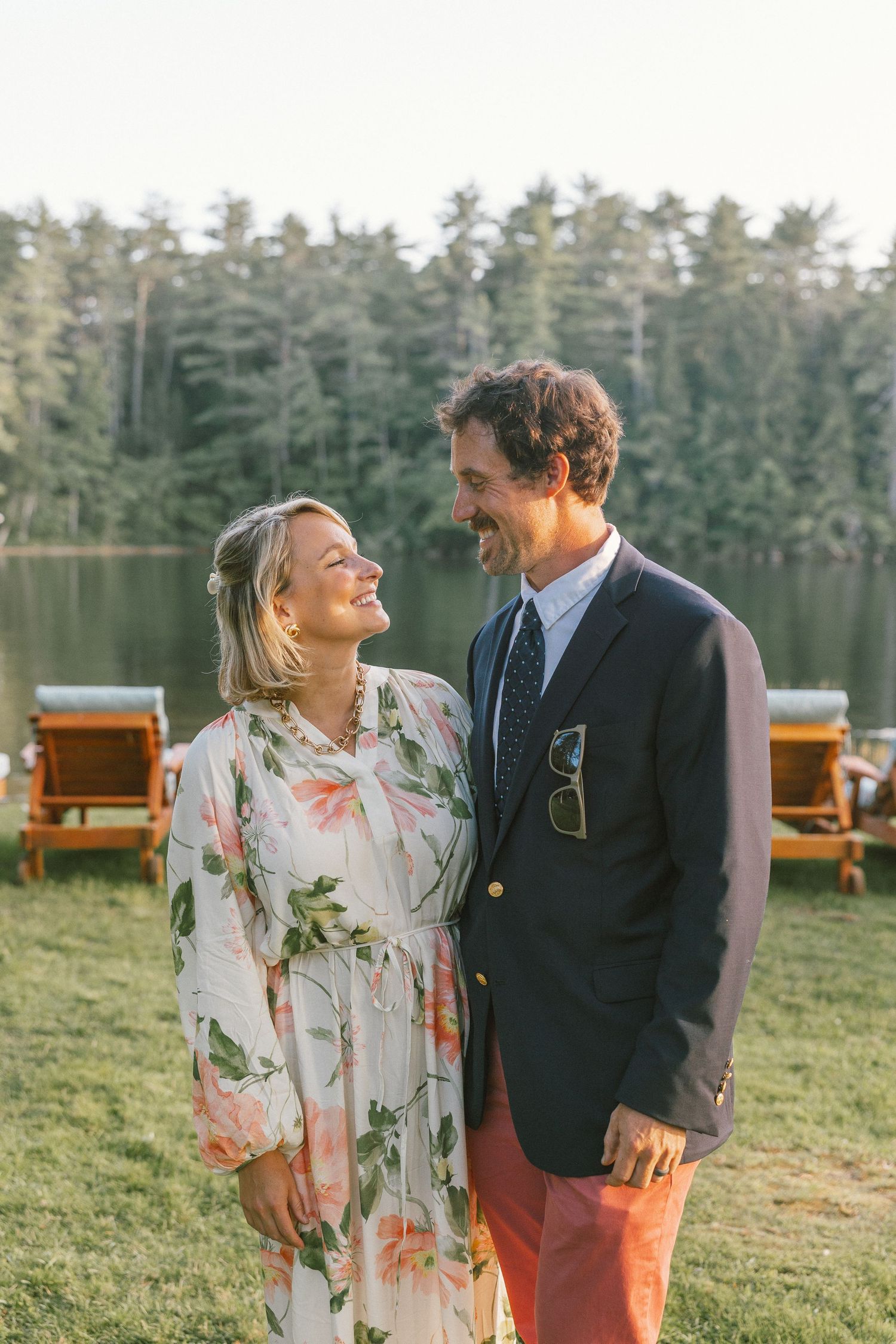 A couple shares a joyful moment outdoors with pine trees in the background.