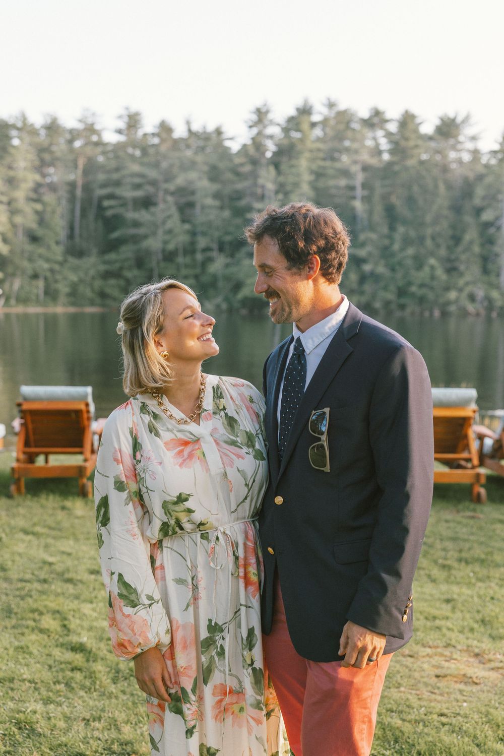 A couple shares a joyful moment outdoors with pine trees in the background.