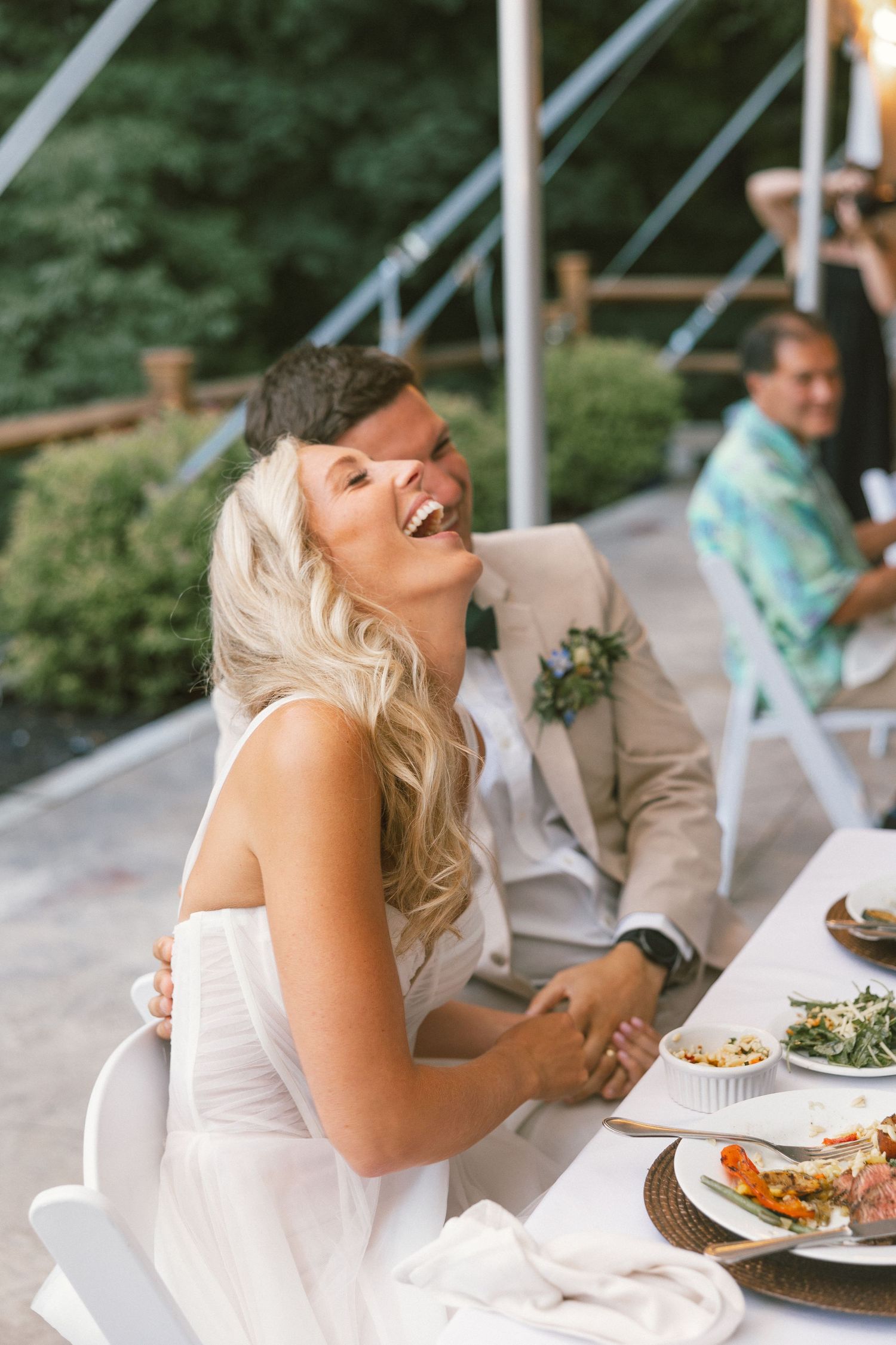 Wedding reception guests enjoying a meal at outdoor tables.