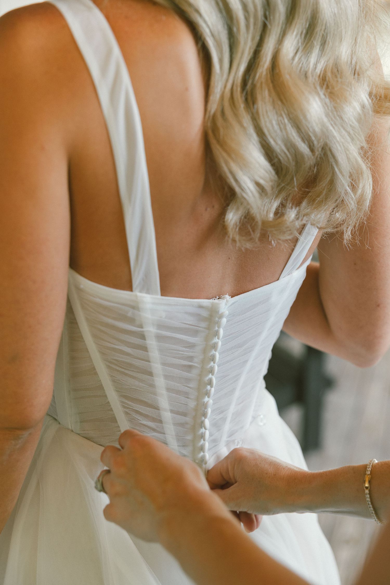Close up of white wedding dress corset back with buttons and lace details.