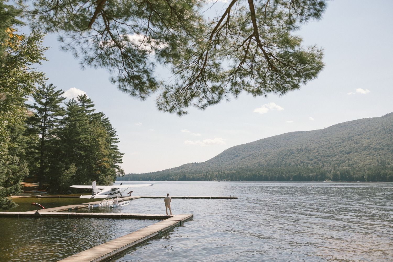 Serene lakeside dock with mountain views and pine trees at the water's edge.