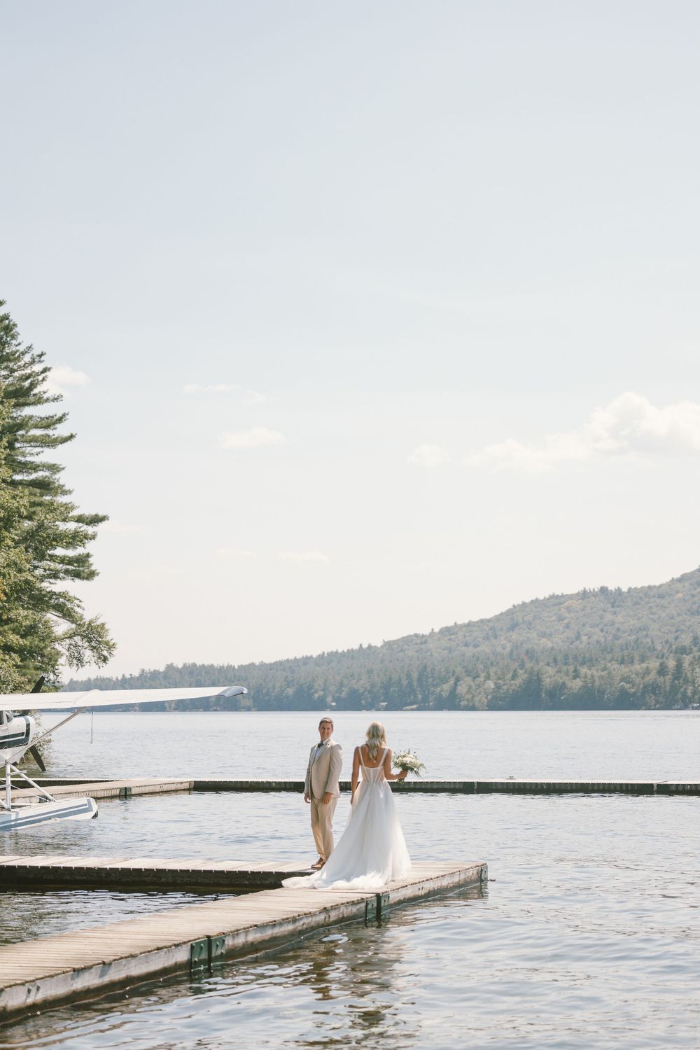 A serene lakeside dock scene with mountain views and pine trees.