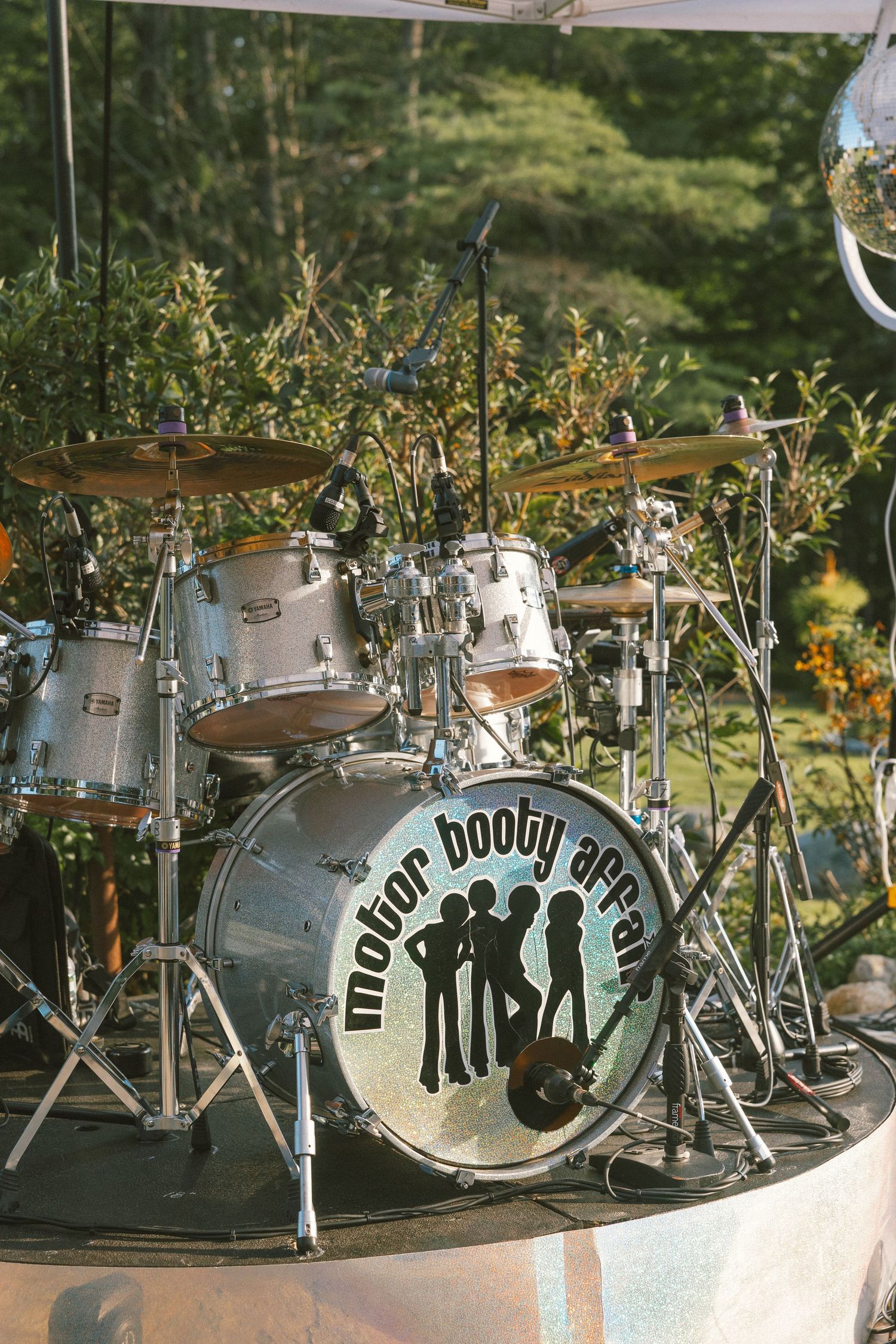 Vintage drum kit with decorative lettering and designs displayed outdoors in a garden setting.
