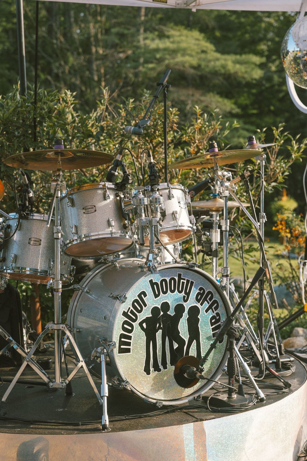 Vintage drum kit with decorative lettering and designs displayed outdoors in a garden setting.