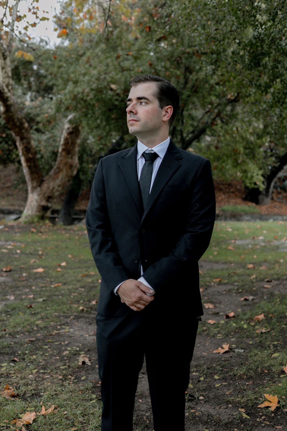 Groom stares off into distance with forest background in Vail, Arizona.