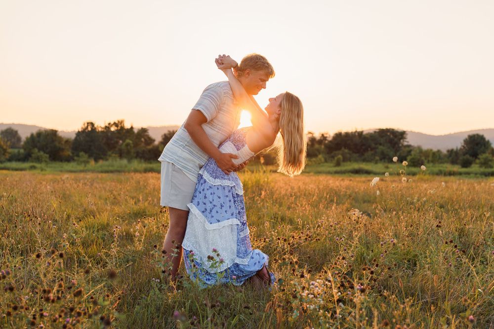 Couple embraces in a golden sunlit meadow during sunset creating a romantic silhouette against the warm sky, in Frederick, MD