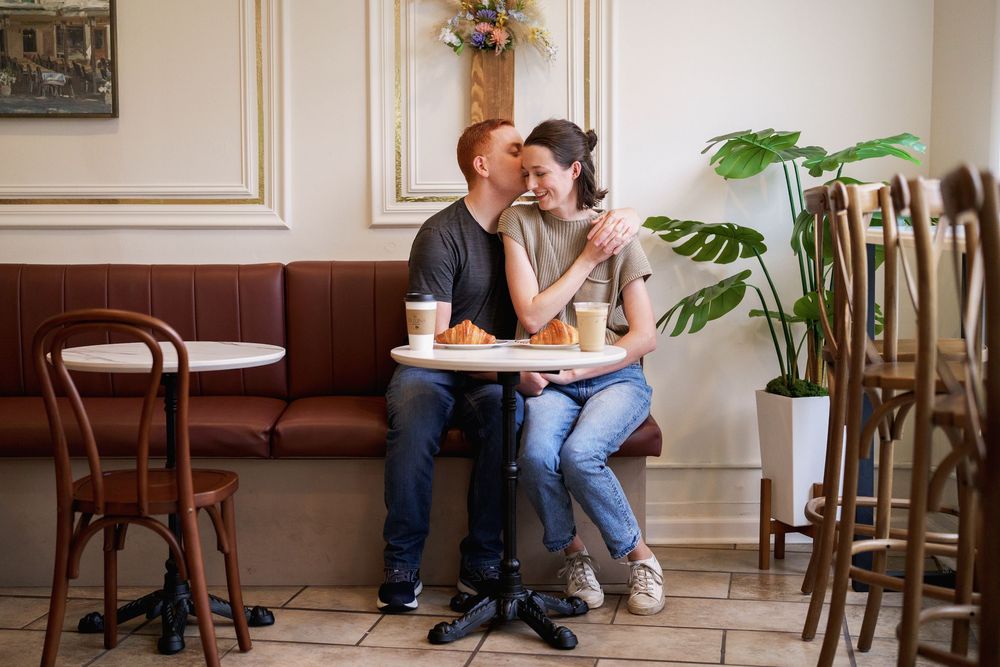 Couple sharing a romantic moment at a cafe table with coffee and pastries on a cozy indoor date, in Frederick, MD