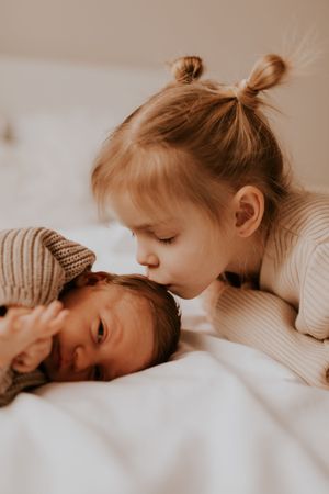 Intimate family moment captured in soft beige tones on white bedding.