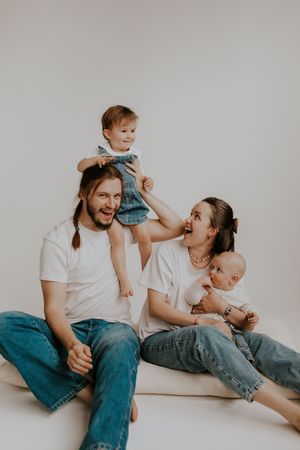 Playful studio session showing family interactions and laughter against white background.