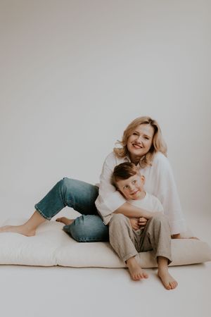 Family members relaxing together on white bedding in casual clothing.