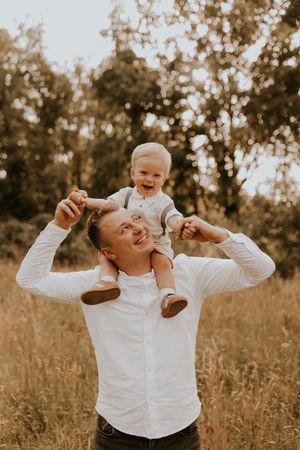 Playful outdoor moments between parent and child in a sunlit field wearing white shirts.