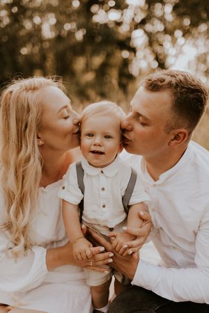Outdoor family photoshoot with golden bokeh background showing joyful moments and kisses.