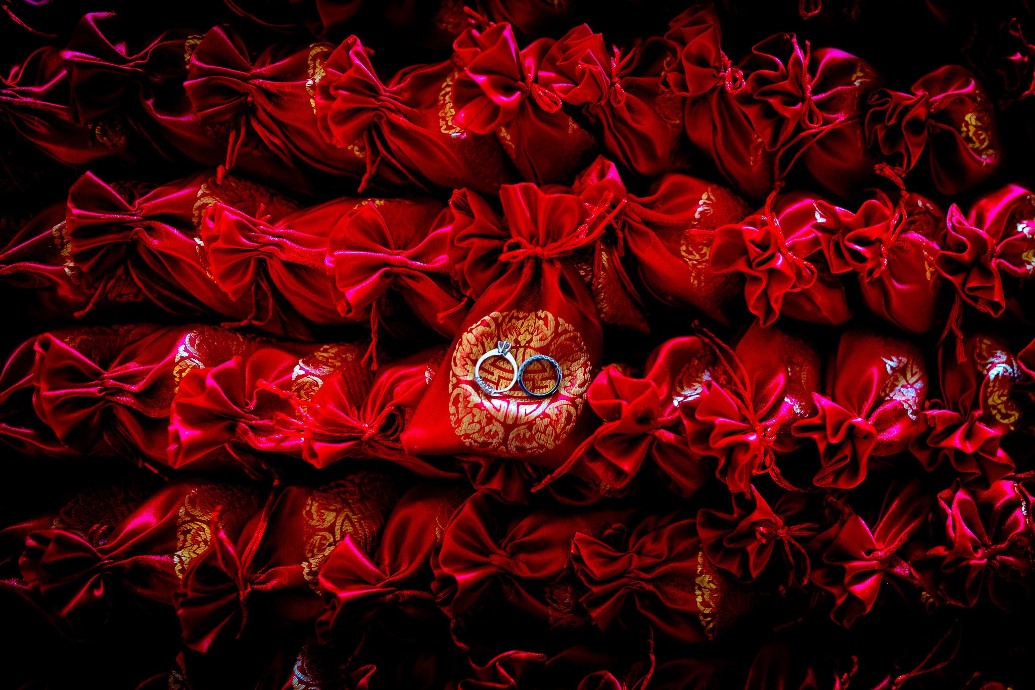 Abstract red light trails with golden wedding rings against a black background.