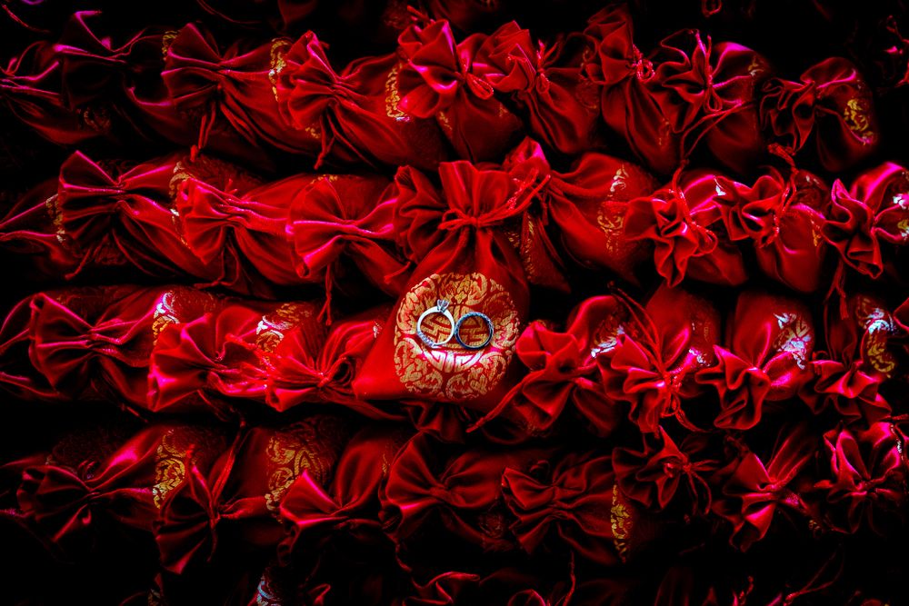 Abstract red light trails with golden wedding rings against a black background.
